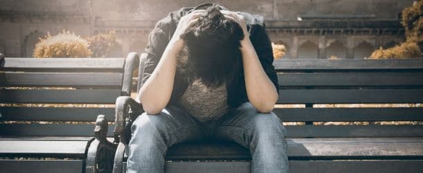 man sitting on park bench upset