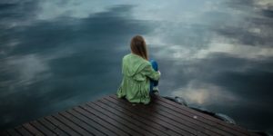 sad woman sitting alone on a pier