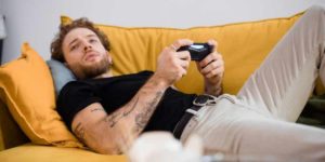 grown man playing video games on couch