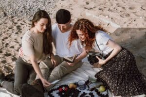 Two young women and one man sitting on a beach