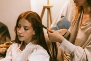 Mother braiding the hair of her teenage daughter