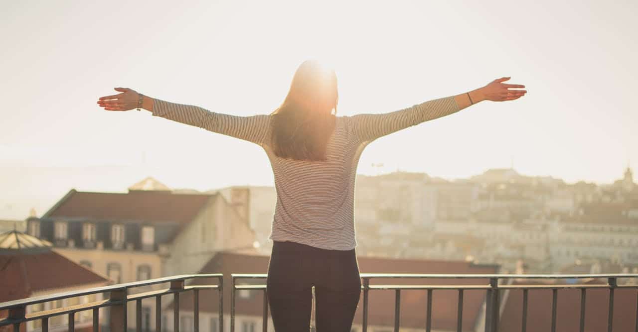 Woman standing on balcony stretching in the morning