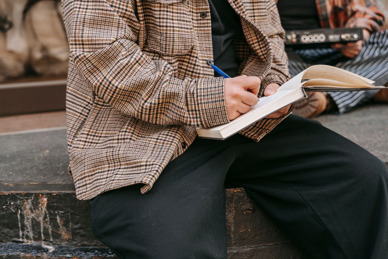 Close-up of a person writing in a notebook with a pen