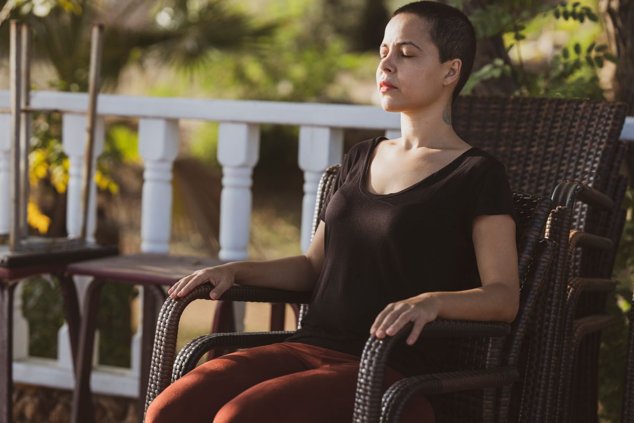 woman sitting on a patio, taking slow, deep breaths