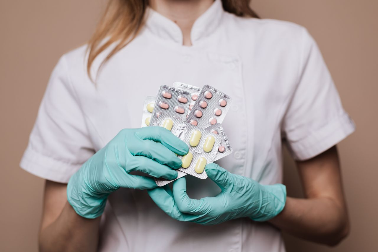 a healthcare professional wearing gloves and holding blister packs of medication